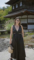 Joyful and confident, a beautiful hispanic woman in glasses stands by the serene ginkaku-ji temple,...