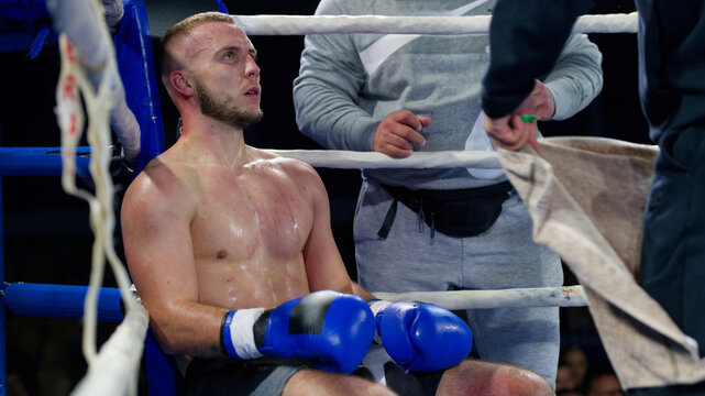 Cornered boxer receives strategic advice from trainer during intense bout.