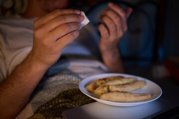 Feeling cozy in bed with a latenight snack, browsing on laptop for a relaxing time