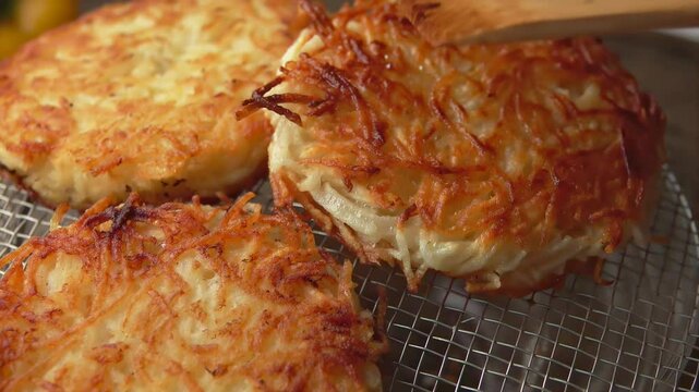 Close up view wooden spatula puts a fried potato pancake on a grate. High quality 4k footage