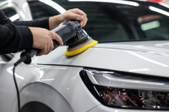 Process of polishing white car hood surface using orbital polishing machine. 