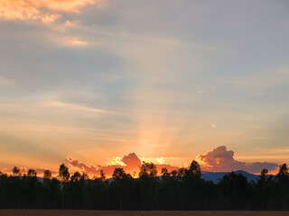 The sun sets and the sky is orange in the countryside in Thailand.