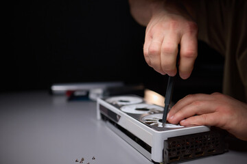 A technician is skillfully repairing a computer GPU fan with precision tools in a workshop
