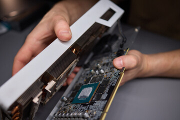A technician is skillfully repairing a computer GPU fan with precision tools in a workshop