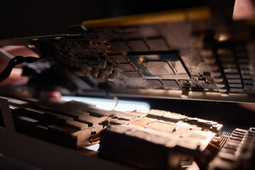 A technician is skillfully repairing a computer GPU fan with precision tools in a workshop