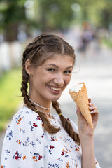 A young girl on the street of the city on a summer sunny day goes and eats ice cream