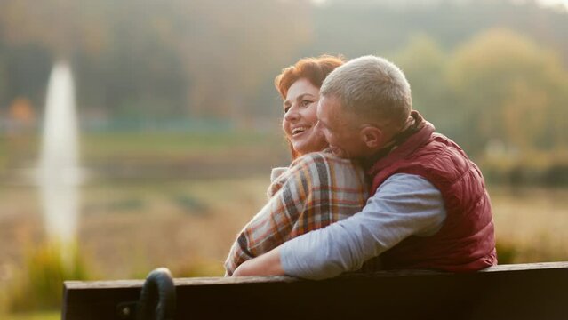 Hello autumn. happy stylish boyfriend and girlfriend in the park embracing while sitting on bench. - Powered by Adobe