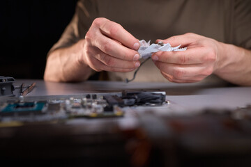 A technician is skillfully repairing a computer GPU fan with precision tools in a workshop