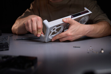A technician is skillfully repairing a computer GPU fan with precision tools in a workshop
