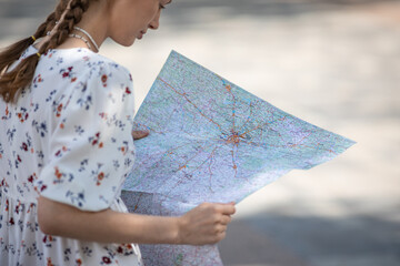 Woman hands with a city map sitting on a bench, travelling on a bright sunny day in city