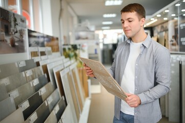 Male architect or interior designer choosing ceramic texture sample from swatch board in design studio