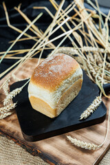 Concept of bread on a wooden table. Ruddy brown loaves of bread stand on a table sprinkled with flour, wheat grains and bread crumbs. Fresh bread concept
