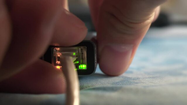 Man disconnects an Internet cable to a laptop using an adapter. Internet cable connection. Internet cable through an adapter connected to laptop. Ethernet cable adapter with green and yellow LED