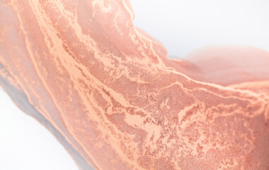 A close-up photo of copper paint swirling and blending with white, creating a smooth, abstract texture