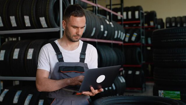 Auto parts seller is checking tires with laptop in the tire warehouse