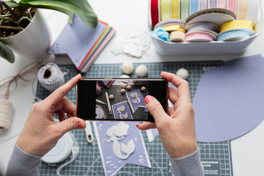 Unrecognizable young woman captures her paper craft project on smartphone