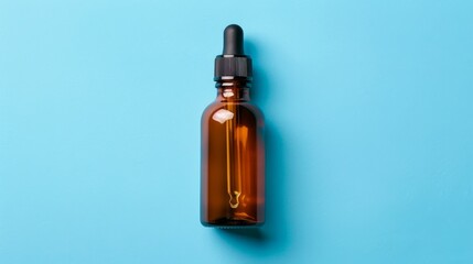 Fototapeta premium Overhead view of oil medicine bottle on blue background with ample space for text placement