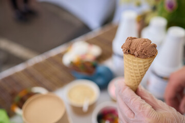 CloseUp of Person Delighting in a Chocolate Ice Cream Cone at an Outdoor Market