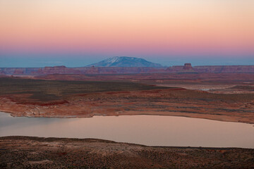 As the sun sets, Lake Powell and the Arizona desert reveal their stunning beauty, offering a serene and peaceful view of natures wonders in this captivating display of colors and contrasts