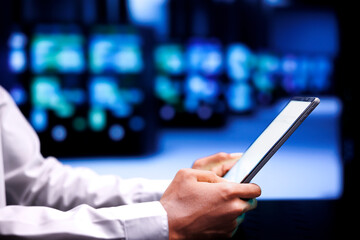 Experienced employee resolving performance related issues in data center mainframes. Admin utilizing mock up tablet to identify operational problems causing equipment slowdown