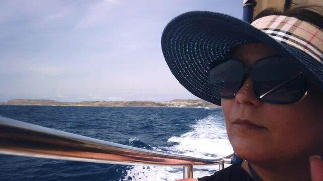 Middle agged woman with sunglasses and hat enjoing boat ride. High quality 4k footage