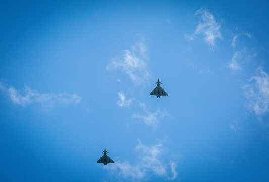 Two RAF typhoons flying, flying in formation back to their respected air fields after taking part in the kings fly past on a beautiful summers day with blue skies and slight cloud