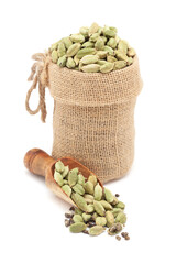 Close-up of Organic Cardamom or cardamum (Elettaria cardamomum), in a jute bag and on a scoop, Isolated on a white background.