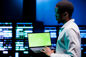 Engineer using green screen laptop to do hardware maintenance in professional data center. Expert...