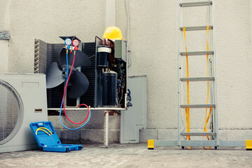 Broken outdoor air conditioner unit in need of fixing next to technician working gear. External...
