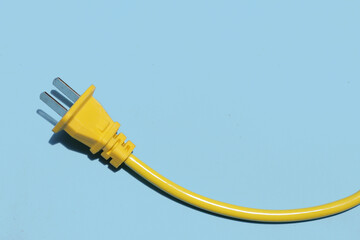 Yellow electric power cable with plug on blue background.