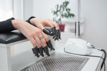 Process removing gel polish from nails in a beauty salon close up. Woman hands with set of plastic...