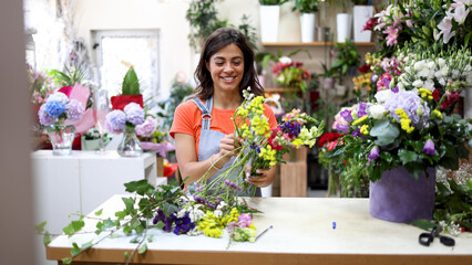 Young florist working at the flower shop and making a beautiful arrangement