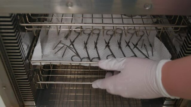 Manicurist preparing instruments for nail care procedures using professional medical equipment. Hardware sterilization of medical manicure tools using the dry heat method