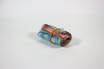 indonesian rupiah banknotes rolled into a tube and tied with a rubber band. Money roll isolated on a white background