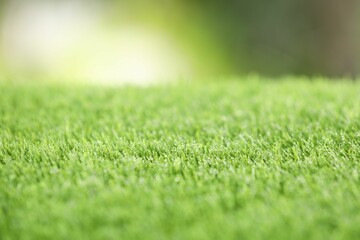 Fototapeta premium Green artificial grass against blurred background, closeup