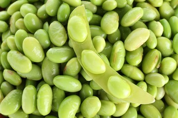 Raw green edamame pod on soybeans as background, top view