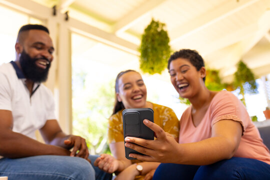 undefined laughing and watching video on smartphone while sitting together indoors