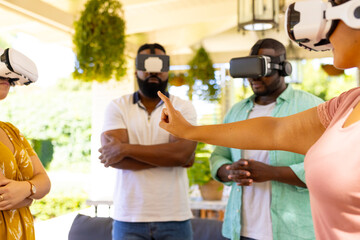 Using VR headsets, group of diverse friends exploring virtual reality together indoors
