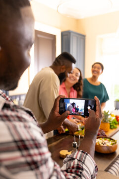 Taking photo, diverse friends cooking and smiling together in kitchen