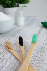 Vertical photograph of three bamboo toothbrushes with organic toothpaste background
