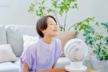 リビングでサーキュレーターを使う女性