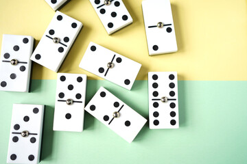 White domino blocks on yellow and green background. There are some benefits of playing domingo; helps to develop critical thinking skills, bond with families and social groups.
