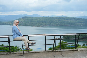 Fototapeta premium Muslim woman enjoying the natural scenery on Bollangi Hill, Gowa Regency