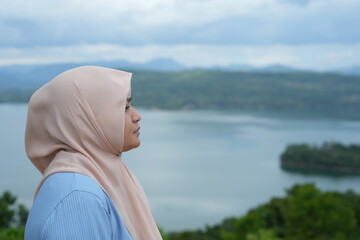 Fototapeta premium Muslim woman enjoying the natural scenery on Bollangi Hill, Gowa Regency