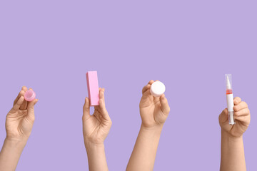 Female hands holding cuticle oil pen, jar of cream and buffer on lilac background