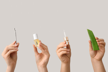 Female hands holding bottle of cuticle oil with pipette, pusher and aloe vera on white background