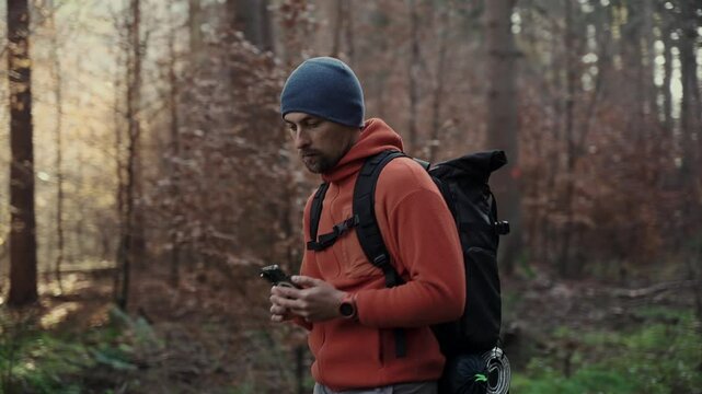Outdoor mapping in hike. Man hiker uses smartphone to navigate in forest using an application and digital maps. Route for hiking in smart phone. Traveler guides in woods by GPS. Travel and explore. 