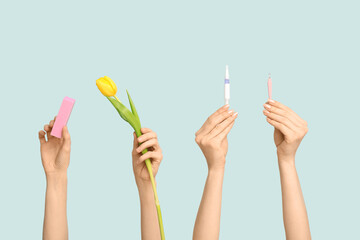 Female hands with cuticle oil pen, nail buffer and tulip on blue background