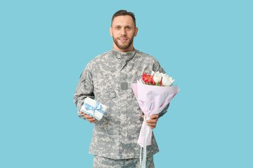 Young male soldier with flowers and gift box on blue background. International Women's Day