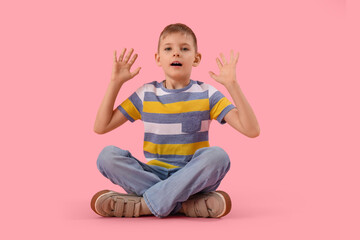 Shocked little boy on pink background